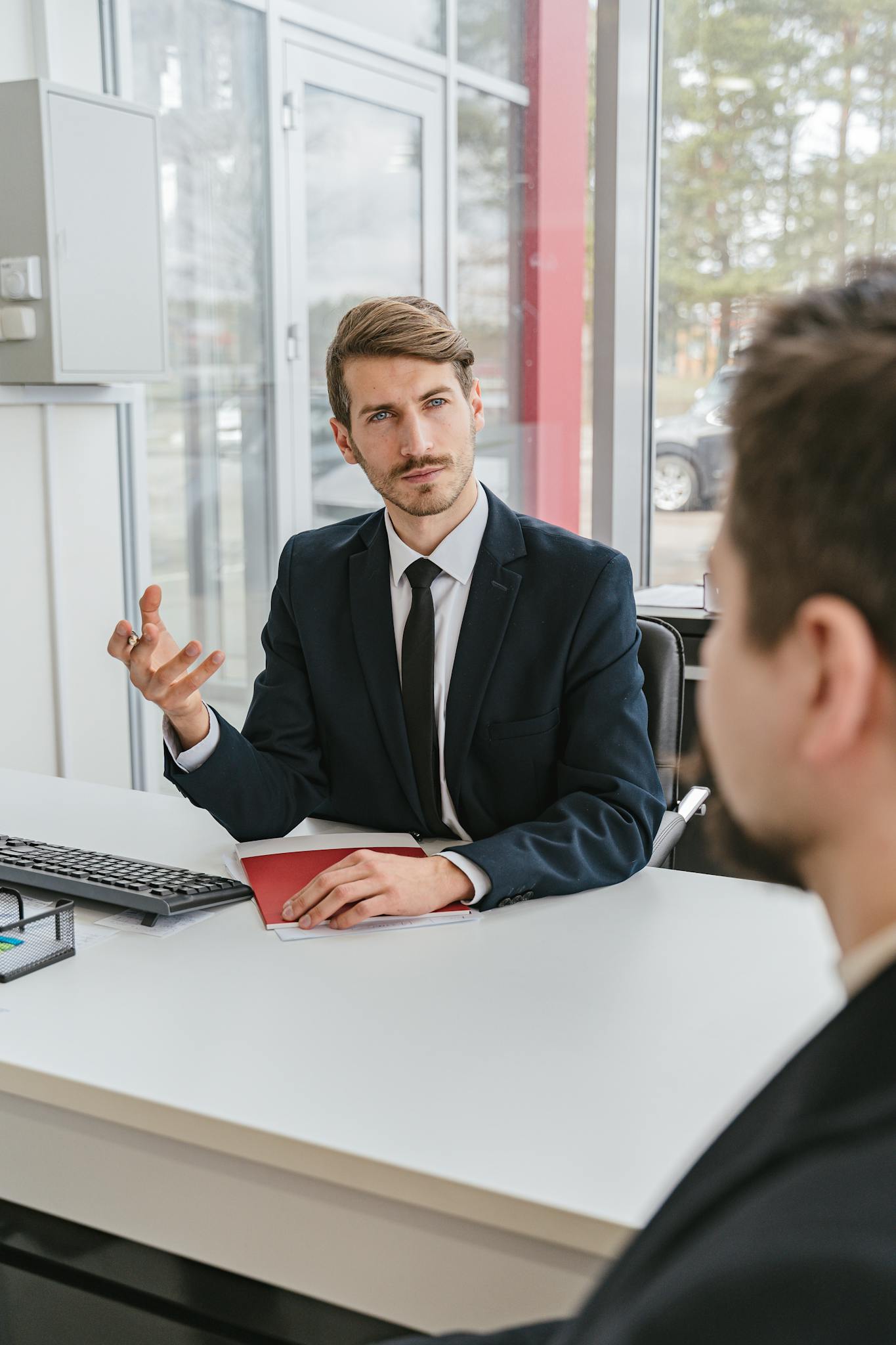 Businessman in a suit consulting a client in a modern office.