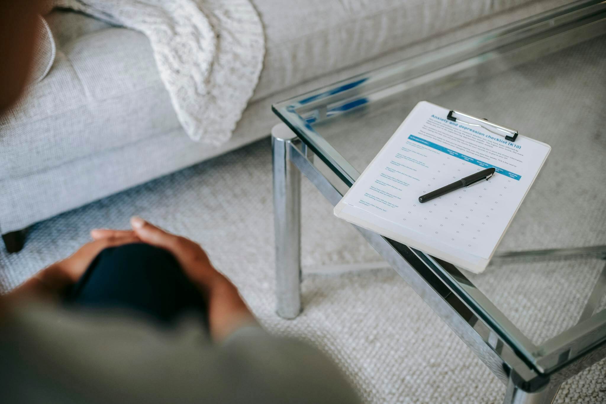 A therapy session setup with a clipboard and anxiety assessment form on a glass table.